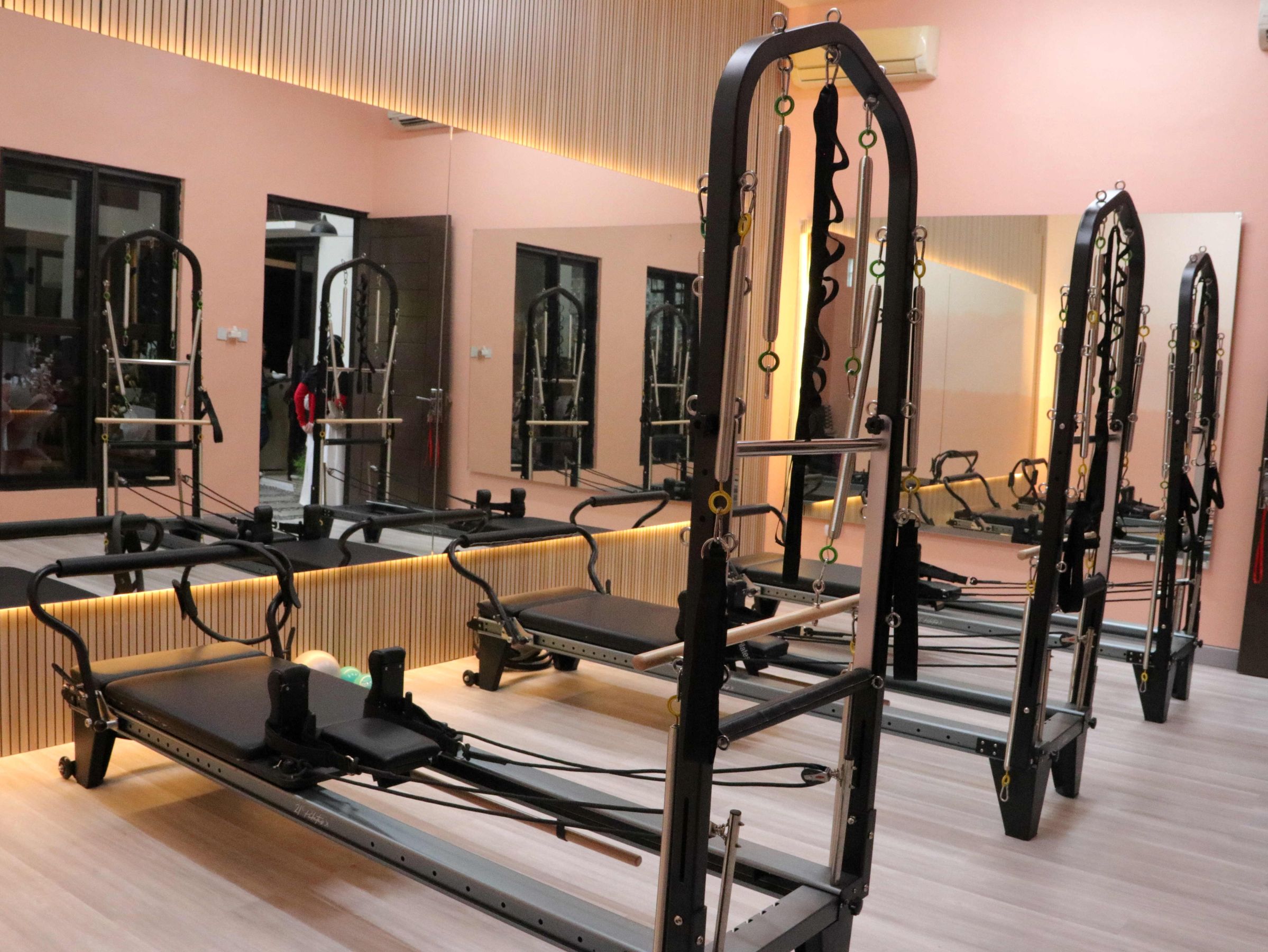 A bright pilates studio with several reformer machines.